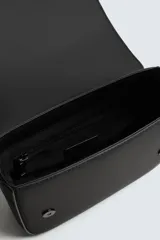 Bandolera verde militar con acabado engomado y textura geométrica. Tiene un compartimento principal con cierre de solapa y botón a presión, un bolsillo interior con cremallera y un asa de hombro ajustable con monedero.