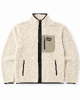 Campera de sherpa color beige con cierre frontal completo, cuello alto y bolsillos laterales con cierre. Presenta un bolsillo frontal superior en contraste color arena con etiqueta de la marca y detalles de ribetes negros.