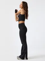 Calza flare deportiva de tiro alto color negro, confeccionada en poliéster con spandex. Presenta pretina ancha, bolsillos laterales y una pequeña apertura en el dobladillo inferior de cada pierna.