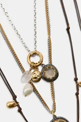 Pack de tres collares de estilo bohemio. Incluye un collar de cordón oscuro con nudos y dijes metálicos, un collar de eslabones metálicos con dijes variados y piedra de resina, y un collar doble de cadenas metálicas con dije de piedra engarzada en resina.