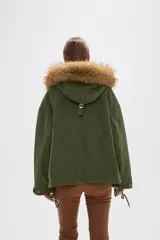 Campera negra de algodón con capucha, cierre frontal oculto y bolsillos laterales. Presenta un diseño holgado con detalles de piel sintética en el borde de la capucha.