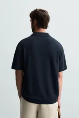 Polo de manga corta color azul marino con tejido de punto jacquard, cuello solapa y cierre frontal de dos botones. Cuenta con acabado en rib en el cuello, mangas y ruedo.