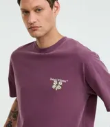 Remera boxy de algodón desteñido color lila, de corte holgado, cuello redondo y manga corta. Cuenta con un pequeño estampado floral en el pecho y un diseño más grande en la espalda.