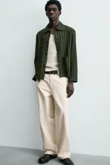 Sobrecamisa de hombre con cuello solapa, manga larga y cierre frontal de botonadura. Presenta un estampado de rayas verticales en tonos de verde oliva y verde oscuro. Incluye bolsillos plastrón en la cadera.