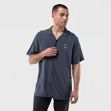 Camisa de manga corta confeccionada en viscosa, con cuello solapa y cierre frontal de botones. Presenta un diseño liso en color gris oscuro con un pequeño estampado circular en el pecho.