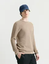 Sweater de punto con textura waffle, color negro, de corte clásico con cuello redondo y mangas largas con puños ajustados.