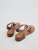 Sandalia de diseño minimalista con tiras anchas de neopreno negro, taco bajo de madera y detalle de tira trasera en color suela.