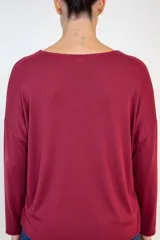 Buzo de lanilla color bordó, con cuello redondo, mangas largas con caída caída y corte holgado.