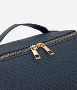 Neceser tipo baúl de color azul marino con textura trenzada. Cuenta con asa superior fija, cierre metálico doble en color dorado y estructura rígida.