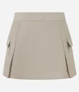 Short pollera beige de sarga con bolsillos cargo laterales y solapa, cintura ancha, pliegues delanteros y cierre frontal discreto.