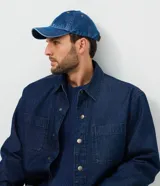 Gorra de sarga de algodón con acabado efecto denim azul, visera curva y paneles estructurados. Cuenta con ojales de ventilación superiores y cierre trasero ajustable.