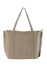 Bolso tipo shopper de gamuza en color gris, con detalles de tachuelas plateadas en los laterales. Cuenta con cierre superior y asas largas para llevar al hombro.