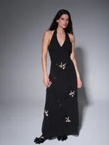 Vestido largo negro con escote halter en V, decorado con costuras en forma de rombos y pequeños bordados florales con lentejuelas.