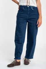 Jean de corte baggy con tiro medio, confeccionado en denim de algodón. Presenta un diseño de pierna ancha con estructura curva tipo barril y cierre frontal con botón y cremallera.