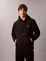 Buzo con capucha negro Calvin Klein, de felpa suave, con cordones ajustables, bolsillo tipo canguro y pequeño monograma bordado en el pecho.