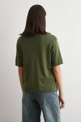 Remera de corte oversized, color verde oliva, con cuello redondo y mangas cortas.