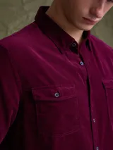 Camisa de pana color azul marino, con mangas largas, cuello clásico y dos bolsillos frontales con solapa y botón.