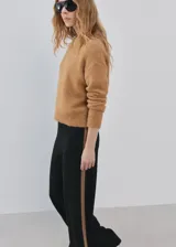 Pantalón de punto negro con diseño recto y holgado, con una franja lateral en tono marrón.