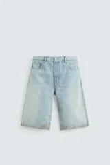 Bermudas de denim de algodón, color celeste claro con efecto lavado y manchas marrones/beige en las perneras. Tienen un corte ancho (baggy fit) y terminación de bajo irregular.