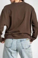 Sweater marrón de algodón con cuello redondo y diseño de moños en relieve bordados en el frente.