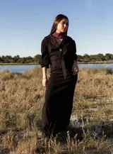 Pollera midi negra con corte evasé, cintura alta y cierre cruzado con botón.