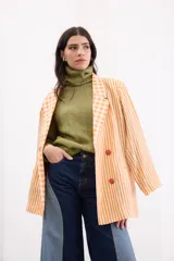 Blazer oversize de lino con diseño combinado de rayas verticales y cuadros vichy en tonos naranja y blanco. Presenta solapas clásicas, cierre frontal de cuatro botones y hombros estructurados.