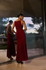 Vestido largo bordó con brillos, escote halter y diseño fluido de corte acampanado.