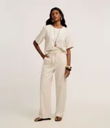 Pantalón pantalona de tiro alto color beige, confeccionado en viscolino, con trabillas en la cintura, cinturón de cuerda ajustable y bolsillos laterales.
