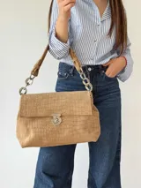 Cartera tipo bolso de cuero tostado con textura símil cocodrilo, solapa frontal con cierre metálico giratorio y manija de hombro combinada de cuero con eslabones metálicos plateados.
