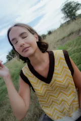 Chaleco de punto sin mangas con escote en V, presenta un diseño estampado geométrico en tonos amarillo y blanco con terminaciones en color marrón oscuro.