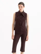 Camisa sin mangas de color marrón oscuro, confeccionada en tejido de punto, con cuello camisero clásico y cierre frontal de botones.