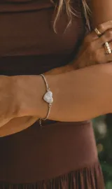 Pulsera de acero ajustable con dije en forma de corazón cubierto de circonias brillantes.