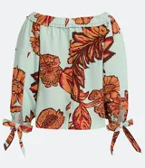 Blusa celeste con estampado de hojas color naranja y marrón, con escote hombro a hombro, mangas 3/4 con lazos en los puños y corte holgado.