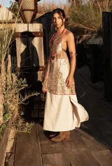 Top de cuero dorado brillante con tela bordada con canutillos dorados que cae a los costados y detalles en cuero rojo. Se ajusta en cuello y espalda.