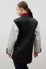 Campera acolchada de corte holgado, color blanco con diseño capitoneado en forma de rombos. Presenta cuello camisero y bordes internos con estampado floral en tonos azul y rojo, cierre frontal con botones a presión y bolsillos laterales.