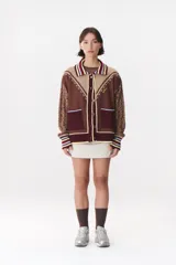 Cardigan de punto con diseño multicolor, cuello tipo polo con rayas, cierre frontal con botones y bolsillos aplicados. Presenta mangas con trama trenzada, coderas en contraste y bordado de la marca en el frente.