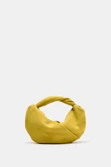 Bolso de mano de piel color verde mostaza, con cuerpo fruncido, asa de mano con detalle retorcido, cadena metálica opcional para función bandolera y cierre mediante cremallera.