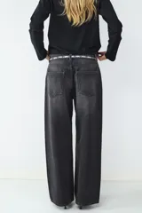 Jean de tiro alto color negro, corte loose con pernera ancha. Diseño clásico de cinco bolsillos con cierre de cremallera y botón metálico.