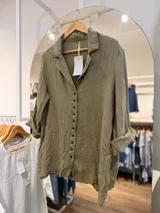 Camisa de lino color verde militar, de manga larga con puños arremangados, cuello camisero y botonera frontal de múltiples botones.