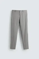 Pantalón de traje slim fit confeccionado en tejido con mezcla de lana. Presenta bolsillos frontales, bolsillos traseros de doble vivo con botón, y cierre frontal con cremallera y botón.