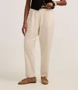 Pantalón zanahoria de cintura alta color crudo, confeccionado en viscolino con trabillas en la cintura, pliegues y solapas traseras. Incluye cinturón fino con hebilla confeccionado en PU.