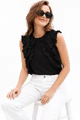 Remera sin mangas blanca con escote a la base y volados aplicados en los hombros.