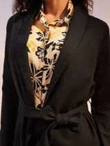 Blazer negro de corte recto con solapas anchas y lazo ajustable en la cintura.
