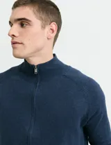 Cardigan de algodón con cuello alto y cierre frontal completo. Presenta mangas largas tipo ranglan y bolsillos laterales de ribete.