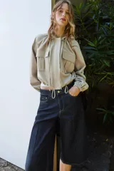 Cazadora color beige con capucha ajustable, manga larga con puño elástico, bolsillos frontales con solapa, bajo ajustable y cierre frontal con cremallera y botones a presión.