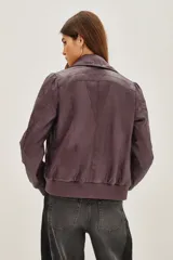 Campera estilo biker color ciruela, con múltiples cierres metálicos decorativos en el frente y mangas. Tiene cuello alto con broches, puños y cintura elastizados.