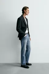 Jeans de mezclilla rígida de algodón, color azul claro con efecto lavado y ligero desgaste. De tiro medio, corte recto desde la cadera hasta la rodilla y ligeramente acampanado en el bajo (bootcut). Cierre frontal con botonadura y cinco bolsillos.