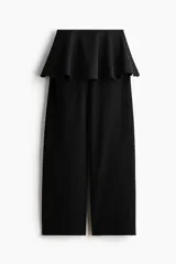 Pantalón negro de corte barrel con pollera mini acampanada superpuesta en la cintura, piernas amplias y cierre lateral.