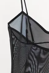 Body tipo shorts de color negro con diseño de efecto visual ondulado. Presenta escote en pico, tirantes finos ajustables y confección en tejido de poliamida con efecto reductor.
