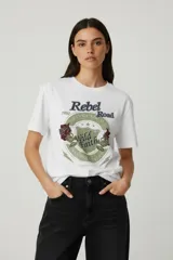 Remera de algodón de manga corta y cuello redondo, con diseño holgado y estampado gráfico frontal con motivos florales y tipografía vintage.